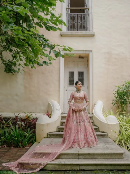 A full-length view of this bride's stunning pastel lehenga with a long, elegant train. Her makeup and hair are styled to match the grandeur of the outfit.