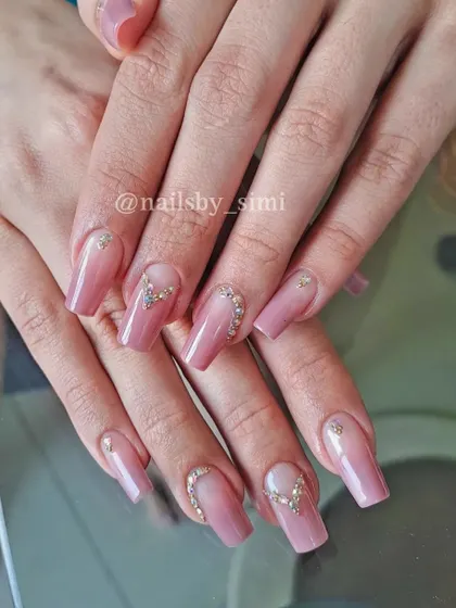 I love the subtlety of these ombre jewel nails. The soft pink ombre provides a beautiful base for the delicate heart-shaped rhinestone placement, making it perfect for an engagement or party.