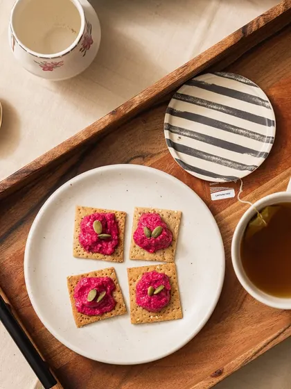 A closer look at our beetroot crackers, served on a tray with a cup of green tea. It's the perfect setup for a mindful and relaxing snack break.