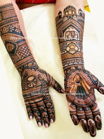 A truly royal bridal design. One palm features a portrait of the bride in a veil, while the arms are adorned with palace architecture, elephants, and a spinning wheel (charkha) motif.