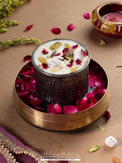 This shot of a festive dessert uses traditional Indian serveware and scattered rose petals to create a rich, celebratory look. It's perfect for promoting special menus during festivals like Diwali or Eid.