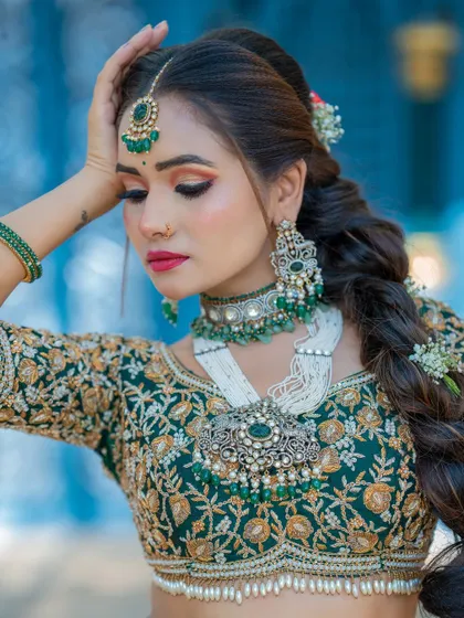 A soft, elegant pose that captures the intricate details of the bridal makeup and the beautiful, heavy necklace. The braided hairstyle adds a touch of modern tradition.