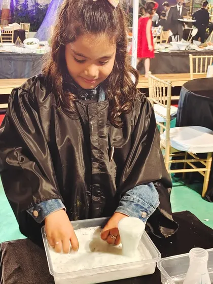 A young guest is fully engaged in a sensory potion-making activity, feeling the unique texture of the fizzing ingredients. It's a safe and tactile way to experience a chemical reaction.