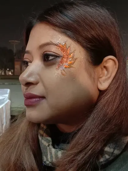 An abstract, flame-like design around the eye using orange glitter. The warm colors create a fiery and passionate look.