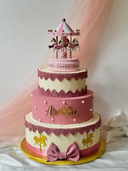 Another view of the stunning three-tiered carousel cake, personalized with the name 'Aneka'. The intricate lacework and golden details make it a true showstopper.