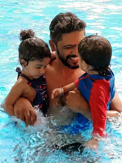 A dad enjoys a playful moment with his two children in the water.