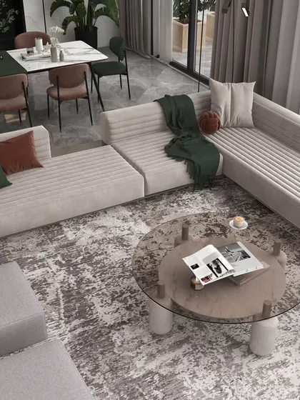 An overhead view of a spacious living room layout, featuring a large sectional sofa and a mix of textures in the rug and cushions.