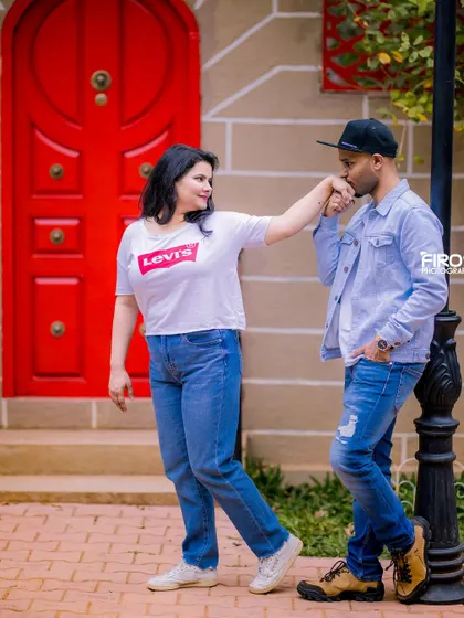 A sweet hand-kiss by a bright red door. This classic romantic gesture looks modern and fun with the couple's casual, stylish outfits.