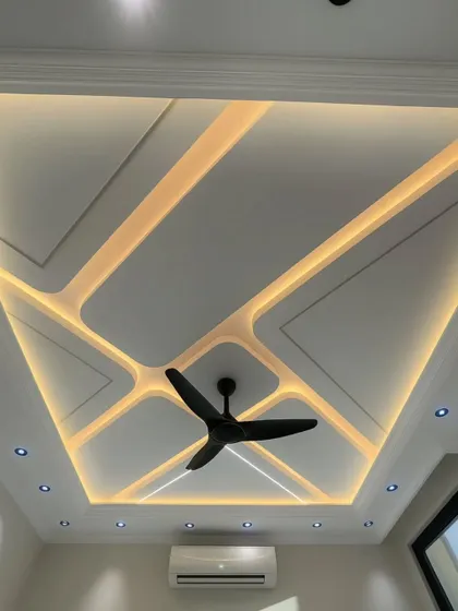 A stunning example of a modern false ceiling design. The geometric pattern with integrated LED strip lighting creates a dynamic and futuristic look, transforming the ceiling into a major design element.