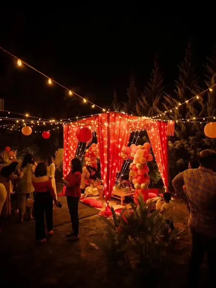 The Barbie party at night, with the pink canopy and surrounding trees illuminated by warm fairy lights, creating a magical ambiance.