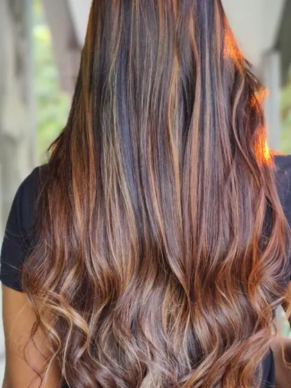 This is a perfect example of a warm, golden-hour balayage. The caramel and honey tones are painted onto long hair, creating a beautiful, sun-kissed effect that looks effortless.