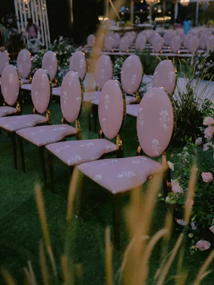 Custom-designed chairs with elegant pink upholstery, created specifically for Nidhi and Amit's ceremony. The floral motif on the fabric tied in perfectly with the surrounding garden installations.