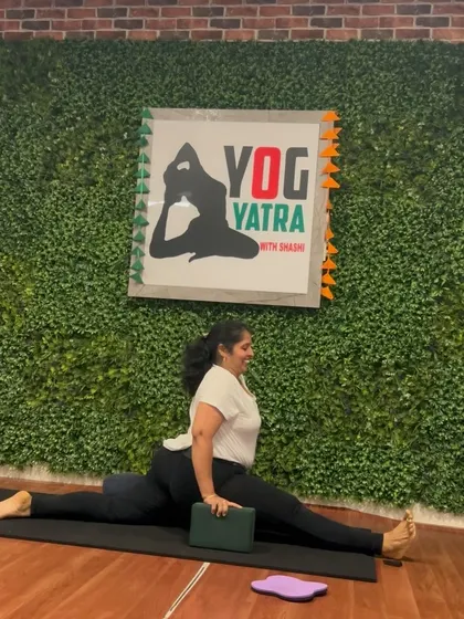 A student uses blocks to support her in Hanumanasana (full splits), showing how props can make advanced poses more accessible.