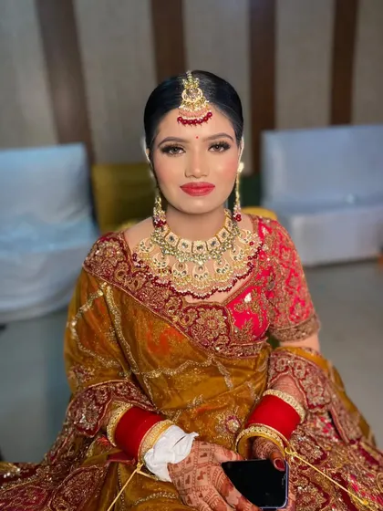 A bride ready for her wedding, featuring a clean, center-parted bun with a maang tikka. This hairstyle is a perfect choice for a classic and sophisticated bridal look.