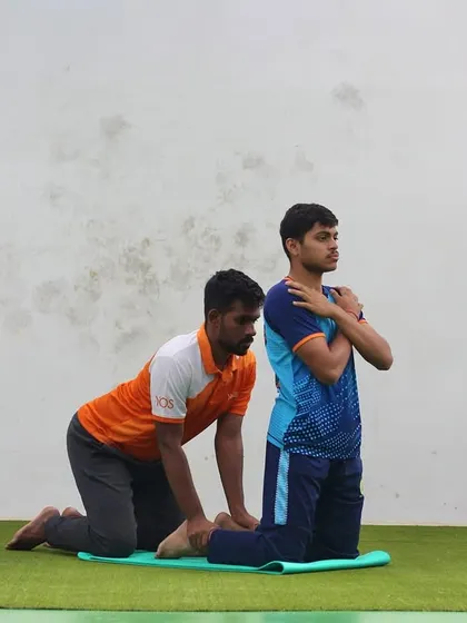 We've got your back, literally. A trainer assists a player with a guided stretching exercise to improve flexibility and prevent back injuries.