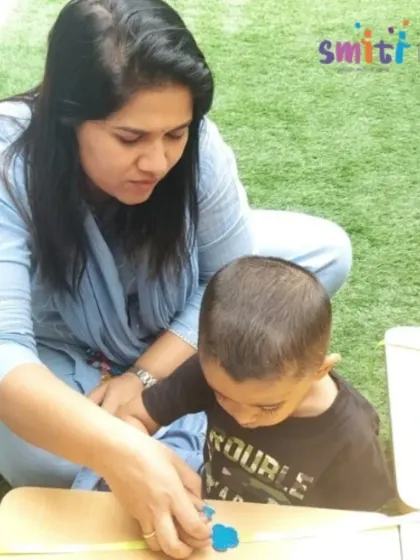 A teacher provides one-on-one assistance to a young boy as he creates his Rakhi. This personalized guidance helps build his confidence and skills.