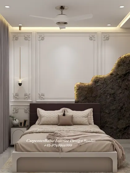 This bedroom has a dramatic and luxurious feel, with a feature wall that combines classic molding with a raw, textured stone-like element.