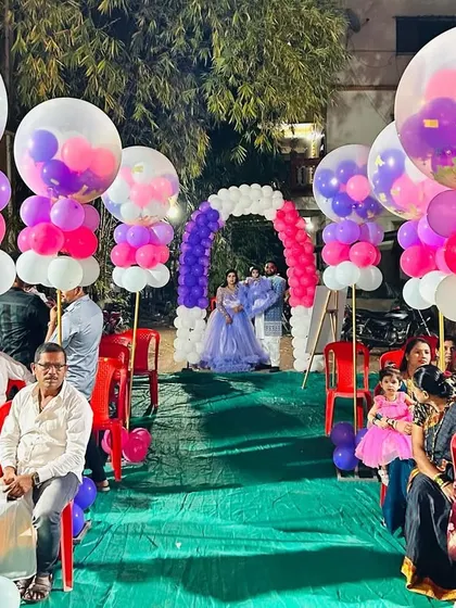 A beautiful balloon-lined walkway for an outdoor birthday party. The large confetti-filled balloons on pillars create a festive and elegant path for guests.