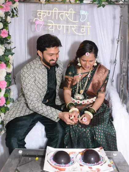 A candid moment of the couple breaking open chocolate spheres, likely for a gender reveal, adding an element of surprise and fun to the event.