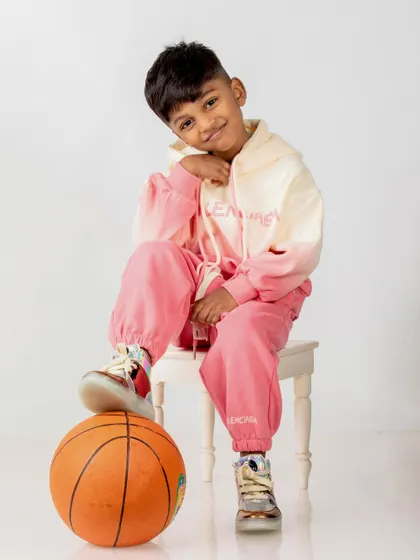 A cool, modern portrait of the 5-year-old in a pink and white tracksuit, posing with a basketball.