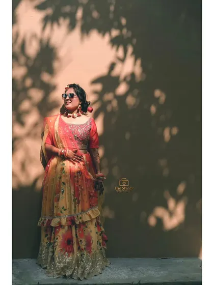 A full-length portrait of the bride against a wall with beautiful leaf shadows. This is a great example of how we use natural elements in our photography.