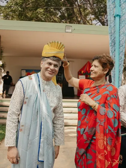 A sweet moment as a woman helps a man adjust his turban, a small act of care during the busy celebrations.