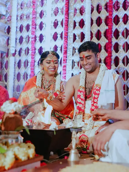 The couple participates in the sacred fire ritual, a central part of their wedding ceremony. The warm glow of the fire illuminates their happy faces.