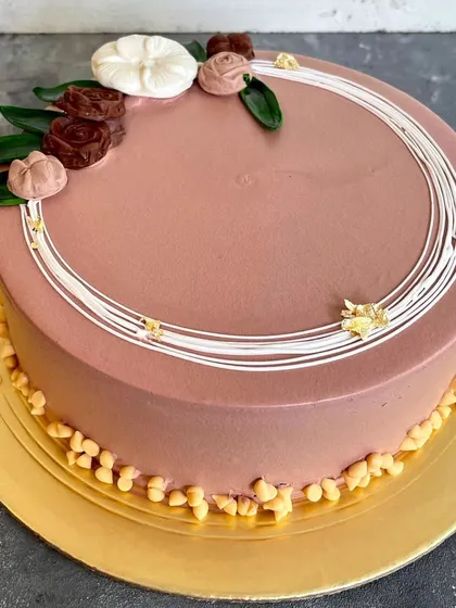 This is our minimalist rosette cake, a simple yet elegant design. It features a smooth chocolate frosting, delicate white line work, and small chocolate rosettes for a sophisticated finish.