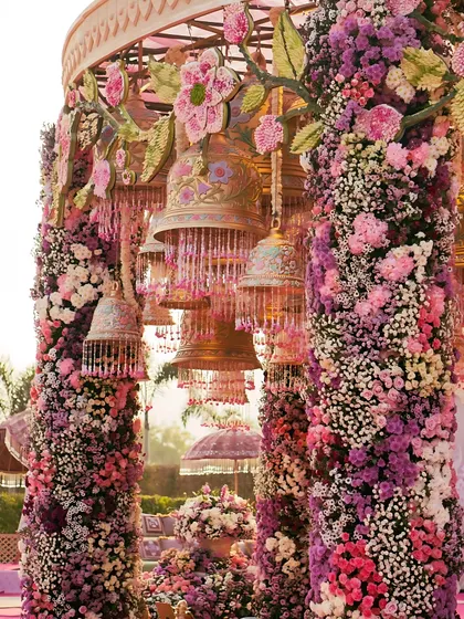 A closer look at the intricate details of our floral mandap. Hand-painted bells hang amidst dense arrangements of roses, hydrangeas, and carnations, showcasing our commitment to craftsmanship and creating layers of beauty for guests to discover.