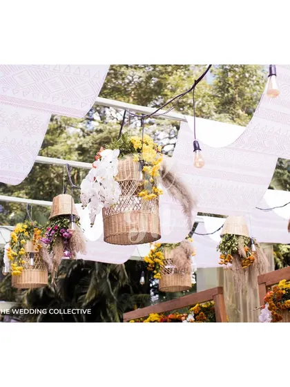The ceiling is adorned with flowing printed drapes and an array of hanging baskets and bulbs. This installation adds a magical, festive feel to the outdoor space, transforming it as the sun sets.