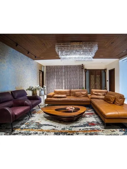 I often mix textures to create a statement. In this living room, a textured blue accent wall and a grand crystal jhoomar contrast beautifully with the warm leather sofa and wooden ceiling, creating a space that feels both grand and grounded.