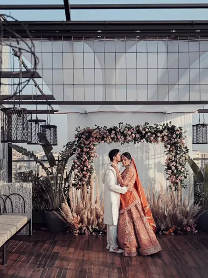 A stunning wide-angle portrait of the couple on a rooftop venue overlooking the city. This shot captures both their intimate moment and the grand scale of their urban wedding.