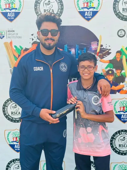 A coach presents an award to a smiling young player for his performance in the RSCA League.
