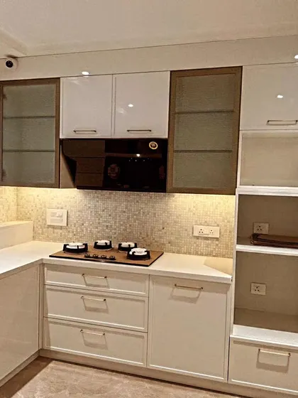 A detailed shot of the cooking zone. The four-burner hob is set against a beautiful mosaic tile backsplash, with open shelving on the side for easy access to everyday items.