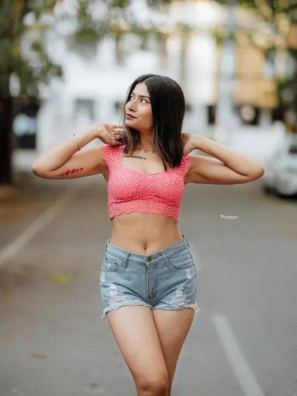 A casual and carefree pose on a quiet street. The blurred background keeps the focus on the model's expression and stylish outfit.