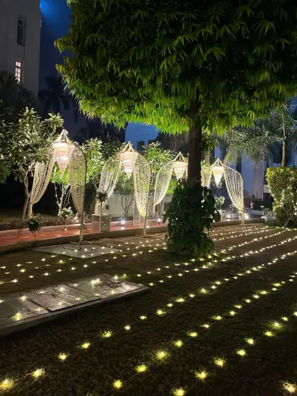 Another view of the magical pathway, with hanging lanterns and a carpet of lights on the grass, leading guests on a journey to an unforgettable evening.