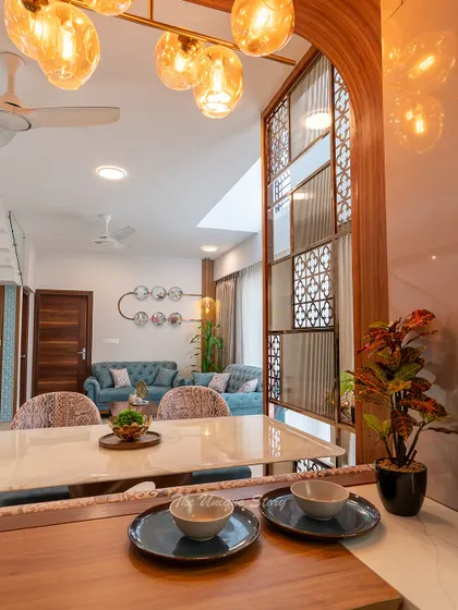Looking from the breakfast nook into the living room, this shot highlights the open-concept design. The decorative jali partition adds a layer of visual interest without obstructing the view, connecting the kitchen, dining, and living areas.
