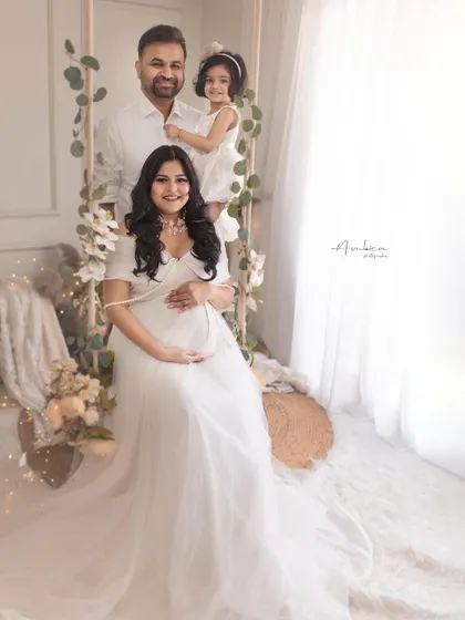 A glowing mother-to-be with her husband and daughter, eagerly awaiting the new arrival. This maternity portrait, styled in all-white, is a beautiful celebration of a growing family.