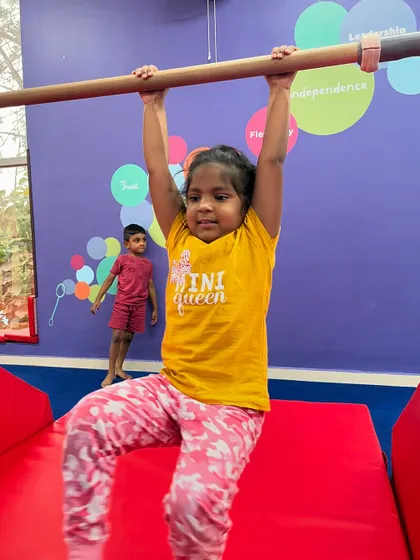 The face of determination. This 'mini queen' is giving it her all as she practices on the bars, building strength and confidence with every swing.