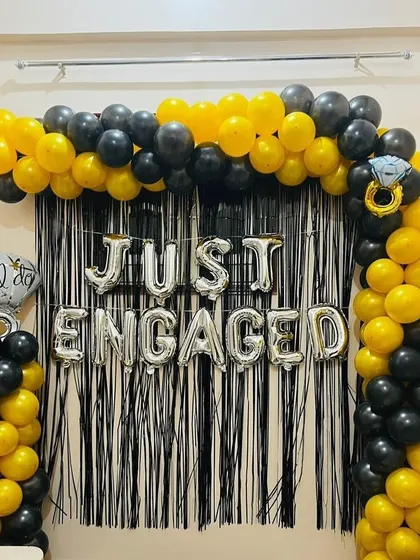 Announce your engagement in style. We created this bold and modern 'Just Engaged' photo backdrop using a black and yellow balloon arch against a black fringe curtain for a high-contrast, celebratory look.