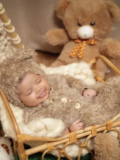 A sweet, smiling baby in a bear costume, nestled in a basket. This close-up captures a moment of pure, sleepy contentment.