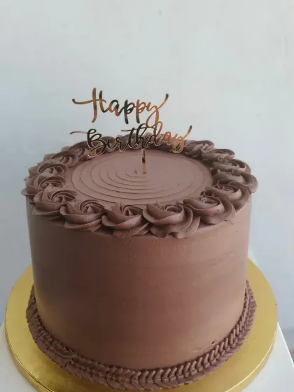 A tall chocolate truffle cake with classic piped rosettes on top and a braided border.