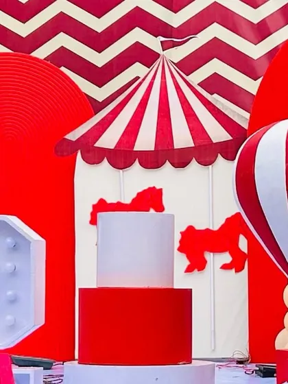 A close-up of the red and white decor elements that define a classic carnival theme, including a carousel-inspired cake stand and chevron patterns.