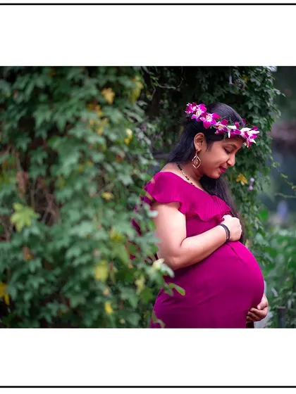 A quiet, contemplative solo portrait, with the mom-to-be looking down at her baby bump with love.