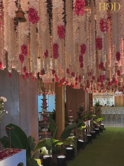 Another view of the floral aisle, highlighting the traditional tiered lamps (diyas) and banana leaf plants that line the path. This blend of elements is perfect for a traditional yet grand wedding ceremony.