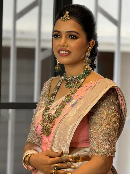 This client looks stunning in her pastel pink and green saree. The custom-designed blouse with intricate embroidery and puffed sleeves adds a touch of modern elegance to her look.