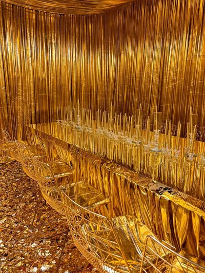 A breathtaking dining setup where the entire room, from the walls and ceiling to the table and chairs, is draped in luxurious gold fabric.