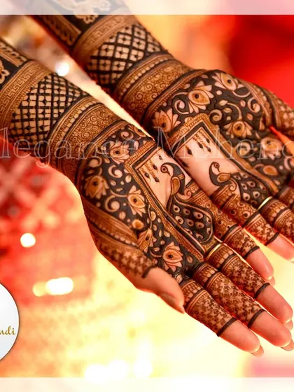 A close-up of the bride's hands, showing the intricate peacock and floral details of her bridal mehendi.