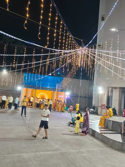 A wide view of an outdoor area decorated for Navratri. The strings of fairy lights create a festive canopy over the entire ground.