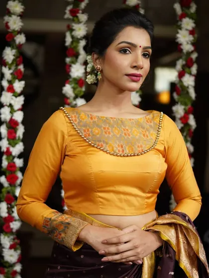 This yellow long-sleeved blouse features a sheer neckline panel with beadwork and printed cuffs, offering a blend of tradition and modernity.
